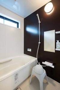 a bathroom with a tub and a stool in it at Aile Hose Ⅱ in Takasaki