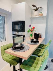 a kitchen with a wooden table and green chairs at Studio apartman Gardenia in Opatija +19 photos