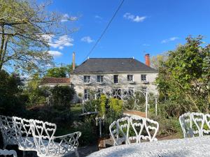 Nueil-sur-LayonにあるChambre de charme dans un jardin de 1500m2の家前白い椅子群