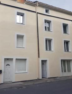 biały budynek z dwoma drzwiami i oknami w obiekcie Appartement en entier w mieście Saint-Junien