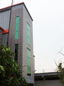 un edificio de ladrillo con ventanas verdes laterales en ApartmenT - Homestays en Sylhet