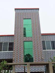 ein großes Backsteingebäude mit grünen Fenstern darauf in der Unterkunft ApartmenT - Homestays in Sylhet