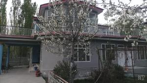 ein Haus mit einem blühenden Baum davor in der Unterkunft Baltistan guest house in Skardu