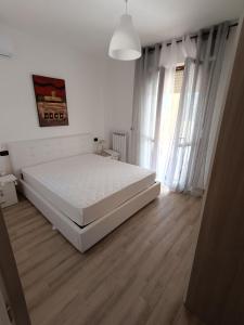 Casa Calatia في Maddaloni: غرفة نوم بسرير ابيض وارضية خشبية