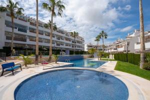 une piscine devant un immeuble avec des palmiers dans l'établissement Linnea sol by Maxim, sea and pool view, Orihuela costa, à Orihuela Costa