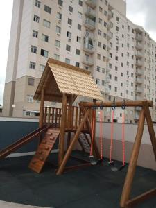 a wooden play structure with a swing and a building at O melhor apt 1 quarto da Serra -ES in Serra