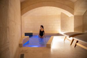 馬泰拉的住宿－Cenobio Hotel & SPA Matera，妇女在室内的热水浴缸中