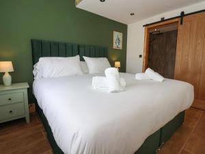 una camera da letto con un grande letto bianco con asciugamani di Nell's Cottage a Malton