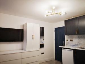 a kitchen with white cabinets and a ceiling fan at Stylish Studio minutes away from Wembley in London