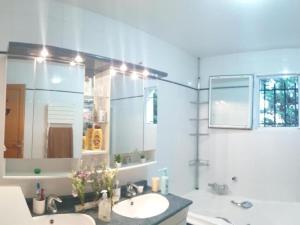 ein Badezimmer mit einem Waschbecken, einer Badewanne und einem Spiegel in der Unterkunft Suite 2 chambres Salle de bain privée Terrasse 30min PARIS in Corbeil-Essonnes