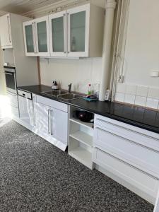a kitchen with white cabinets and a black counter top at KM Rentals - Lillestrøm City - Private Rooms in Shared Apartment in Lillestrøm