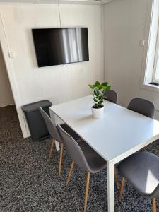 Biały stół z krzesłami i telewizor na ścianie w obiekcie KM Rentals - Lillestrøm City - Private Rooms in Shared Apartment w mieście Lillestrøm
