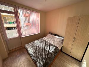 - une chambre avec un lit, une armoire et une fenêtre dans l'établissement Апартамент Lotus, à Varna