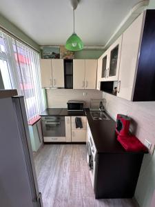 une cuisine avec des armoires blanches et un comptoir noir dans l'établissement Апартамент Lotus, à Varna