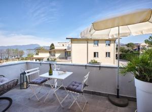 une terrasse avec une table, des chaises et un parasol dans l'établissement STUDIO THE BEACH - Regarda Travel, à Bardolino