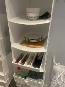 a white kitchen pantry with plates and utensils at Tift bossgård in Linköping