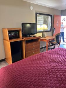 a hotel room with a bed and a tv and a desk at Rodeway Inn & Suites Greensboro Southeast in Greensboro