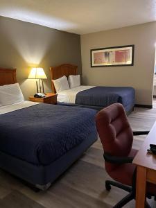 a hotel room with two beds and a chair at Rodeway Inn & Suites Greensboro Southeast in Greensboro