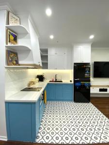 een keuken met blauwe kasten en een zwarte koelkast bij Dino Home Hilton Luxury in Hai Phong