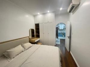 Dormitorio blanco con cama y pasillo en Dino Home Hilton Luxury, en Hai Phong