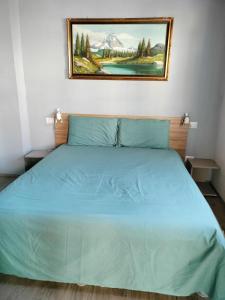 Un dormitorio con una cama azul con una pintura en la pared en CASCINA PONTETTO, en Asti