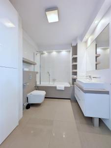biała łazienka z wanną, toaletą i umywalką w obiekcie Turnau City Aparthotel w Krakowie
