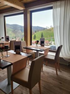 una stanza con tavoli e sedie e una grande finestra di Schwarzwald Hotel Wiedenerhof a Wieden