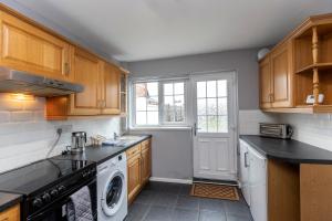 a kitchen with wooden cabinets and a washer and dryer at Park Green in Stockton-on-Tees