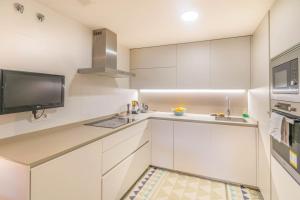 a kitchen with white cabinets and a flat screen tv at Descansa en un sitio agradable in Pamplona