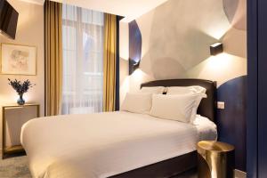 Un dormitorio con una cama blanca y una ventana. en Hôtel Le Nautilus, en Saint-Malo