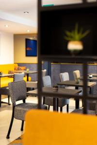 サン・マロにあるHôtel Le Nautilusのテーブルと椅子、薄型テレビ付きのレストランを提供しています。