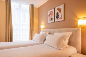 a bedroom with a bed with white pillows and a window at Hôtel Le Nautilus in Saint Malo