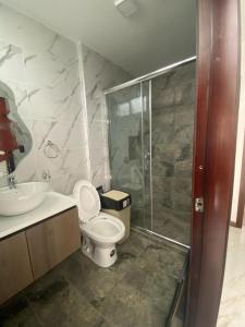 y baño con aseo, lavabo y ducha. en Pent House Exclusivo en Loja