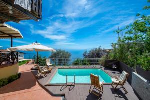 un patio con piscina, sillas y sombrilla en Solaria, en Amalfi