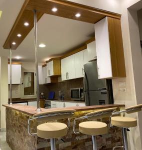 a kitchen with white cabinets and a counter with stools at مارينا 5 الساحل الشمالي in El Alamein