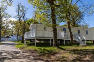 a mobile home with a wrap around porch and trees at 10 Beachlands in Porchfield