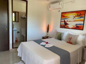 um quarto com uma cama branca e uma pintura na parede em Kailua apartamentos e suítes em Porto de Galinhas