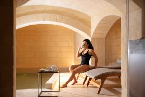 une femme assise sur une chaise dans une salle de bain dans l'établissement Cenobio Hotel & SPA Matera, à Matera