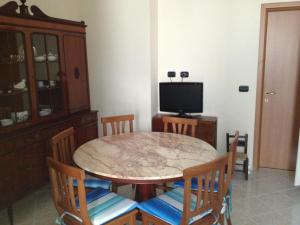 una sala da pranzo con tavolo, sedie e TV di Casa Vacanze Mare Trinitapoli a Trinitapoli