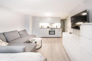 a white living room with a couch and a kitchen at Nordnes Studio Apartment in Bergen