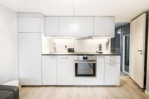 a white kitchen with white cabinets and appliances at Nordnes Studio Apartment in Bergen