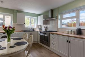 a kitchen with white cabinets and a table with chairs at Ivy House in Northampton