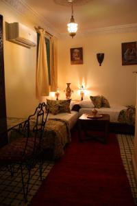 a bedroom with two beds and a red rug at Ryad Meknassia in Meknès