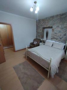1 dormitorio con cama y pared de piedra en Casa do Ribeiro en Chão de Couce