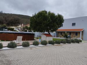 a tree and a white chair in a courtyard at Casa do Ribeiro in Chão de Couce
