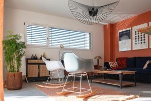 a living room with orange walls and white chairs at Villa Claber in Huningue