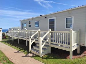 a mobile home with a white railing and stairs at Torbay Holiday Home at The Waterside Holiday Park - With Deck and Sea View in Torquay