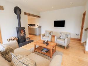 a living room with a wood stove and two chairs at Lime Cottage in Backbarrow