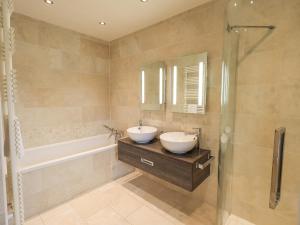 a bathroom with a sink and a tub and a mirror at Lime Cottage in Backbarrow +29 photos