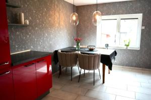 una cucina con tavolo nero, sedie e armadi rossi di Berga Farmhouse a Berga